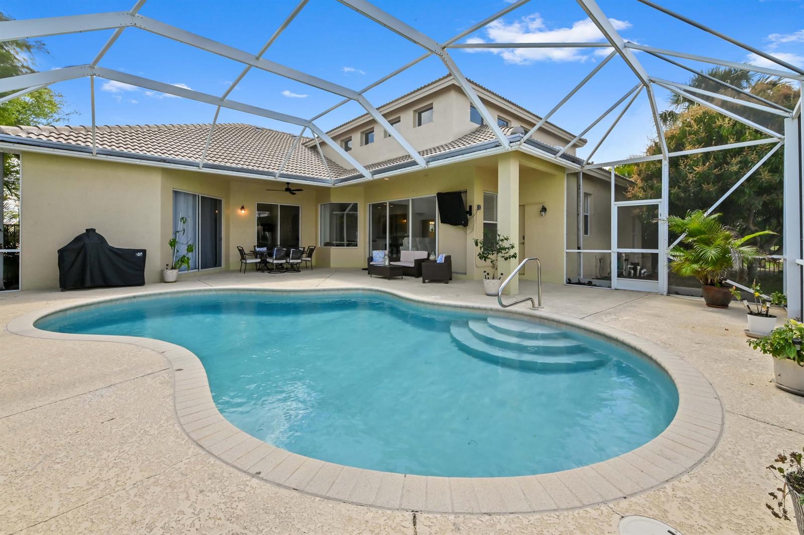 A screened-in patio features a kidney-shaped swimming pool and outdoor seating area — 3638 Hamilton Key, West Palm Beach FL 33411, WEST PALM BEACH, FL