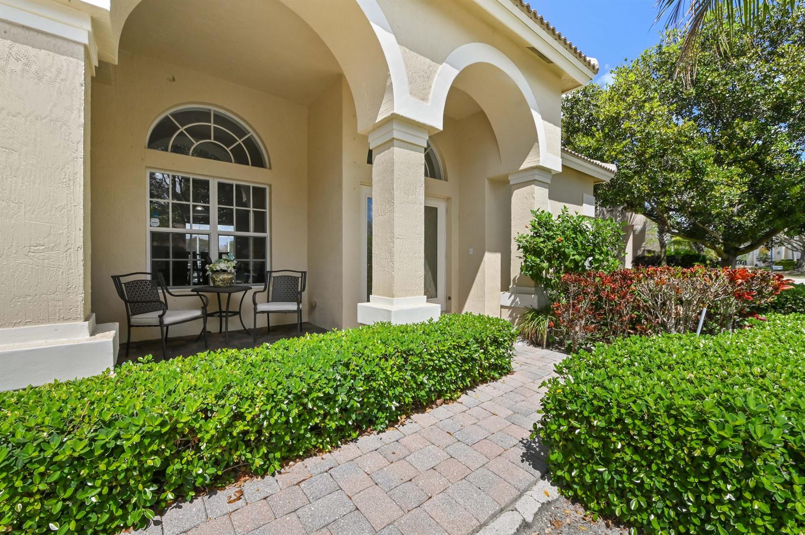 A paved walkway leads to a covered front porch with arched columns and outdoor seating — 3638 Hamilton Key, West Palm Beach FL 33411, WEST PALM BEACH, FL