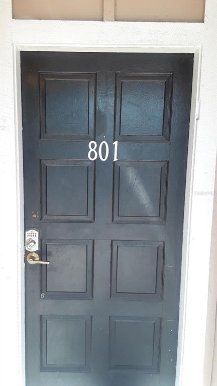 A dark-painted front door with six panels and the number 801 features a keypad lock — 200 COUNTRY CLUB DRIVE UNIT 801, LARGO, FL