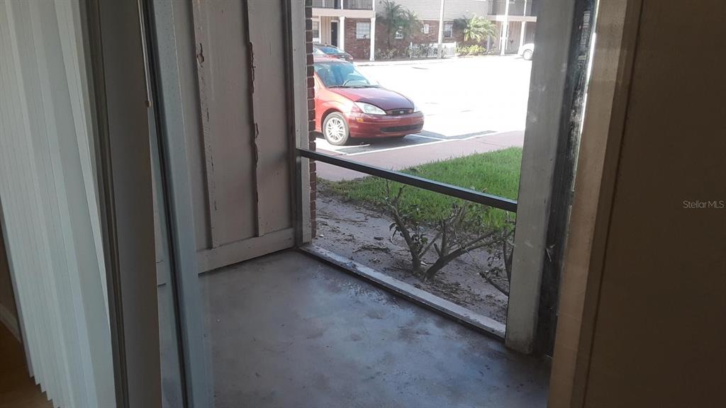 A view from a covered patio looking out toward a parking lot and a red car — 200 COUNTRY CLUB DRIVE UNIT 801, LARGO, FL