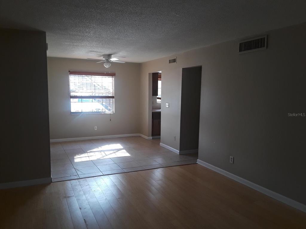 A living room with wood flooring transitions into a tiled dining area with a window — 200 COUNTRY CLUB DRIVE UNIT 801, LARGO, FL