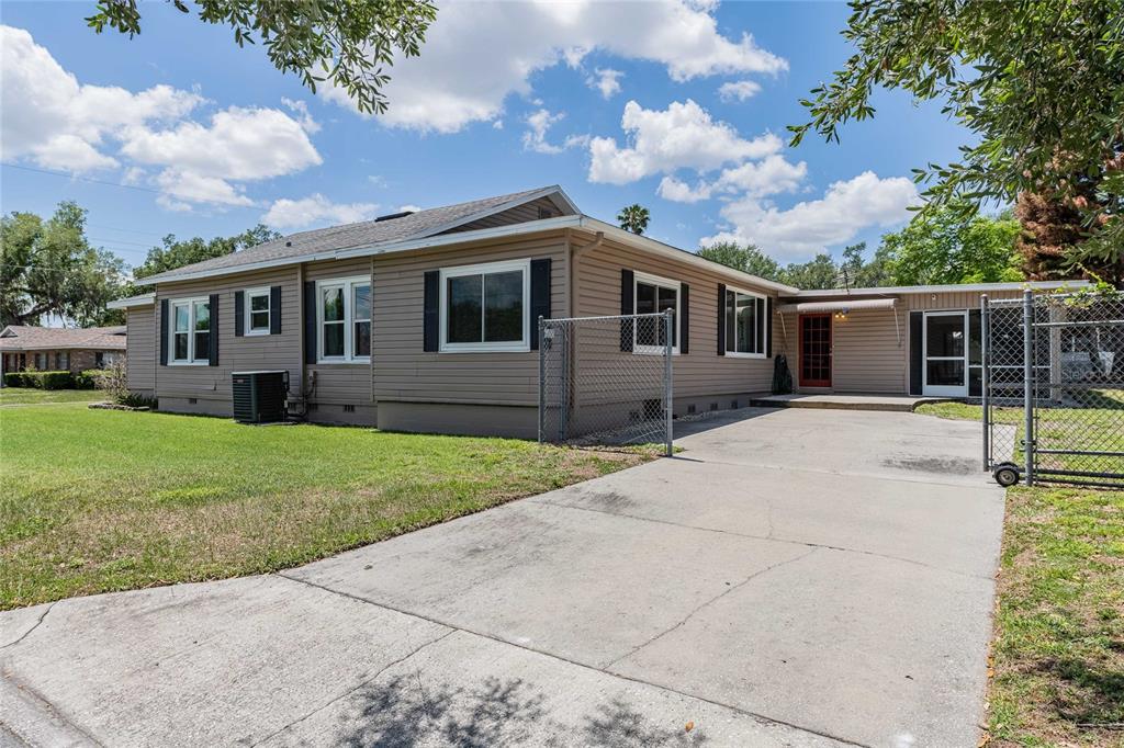 A tan, single-story house with a concrete driveway and a chain-link fence — 848 VALENCIA STREET E, LAKELAND, FL
