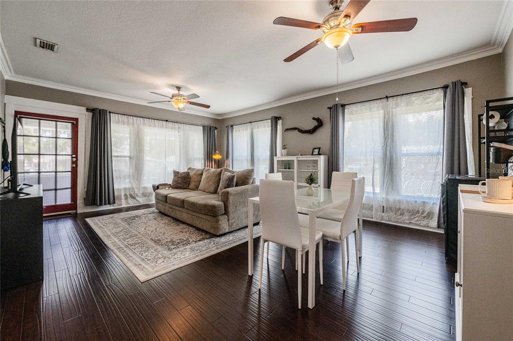 A living and dining area with dark wood floors, a beige sofa, and white chairs — 848 VALENCIA STREET E, LAKELAND, FL