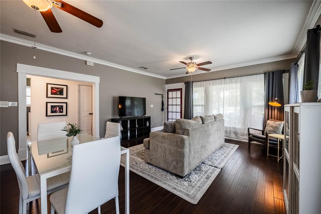 A living and dining area with dark wood floors, a gray sofa, and white chairs — 848 VALENCIA STREET E, LAKELAND, FL