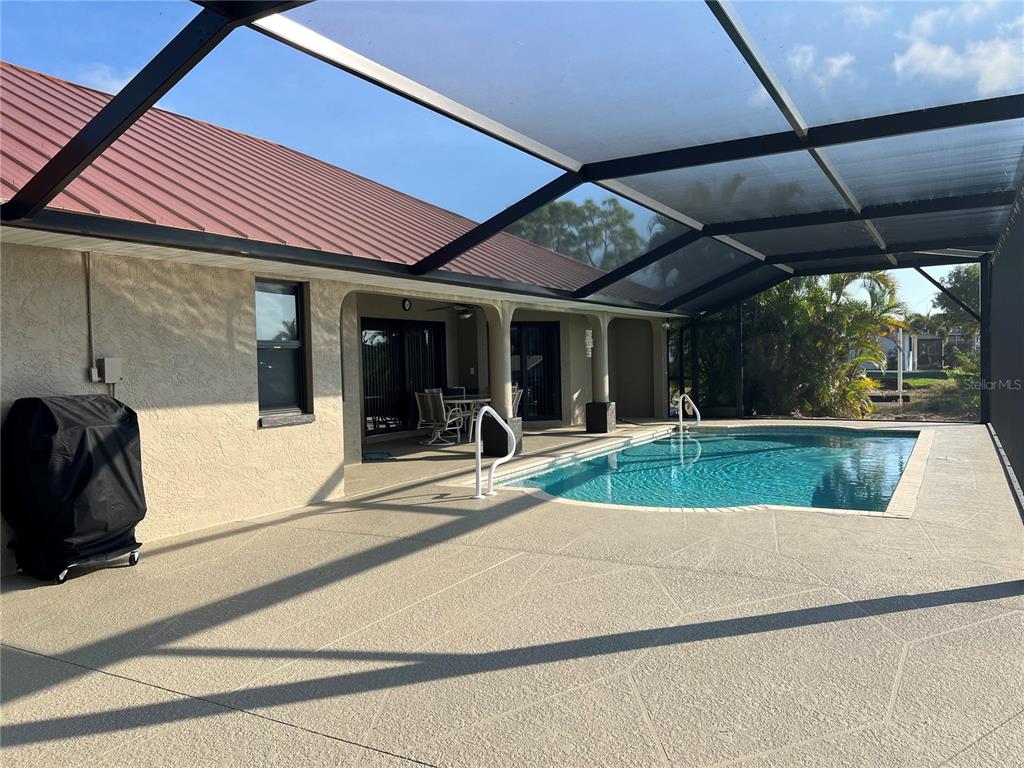 A covered patio features a swimming pool, a grill, and a metal roof — 426 NW 37TH PLACE, CAPE CORAL, FL
