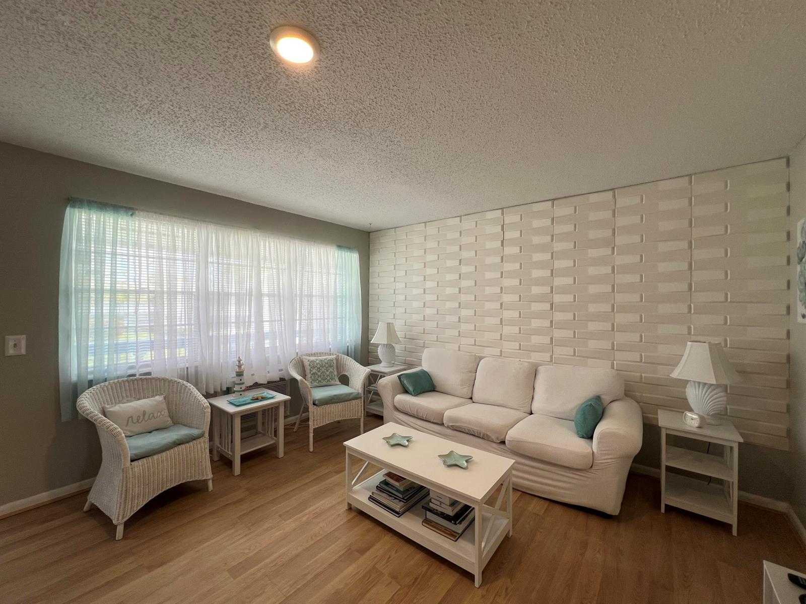 A living room features a white sofa, two wicker chairs, a coffee table, and textured walls — 258 Markham L # 258, Deerfield Beach FL 33442, DEERFIELD BEACH, FL