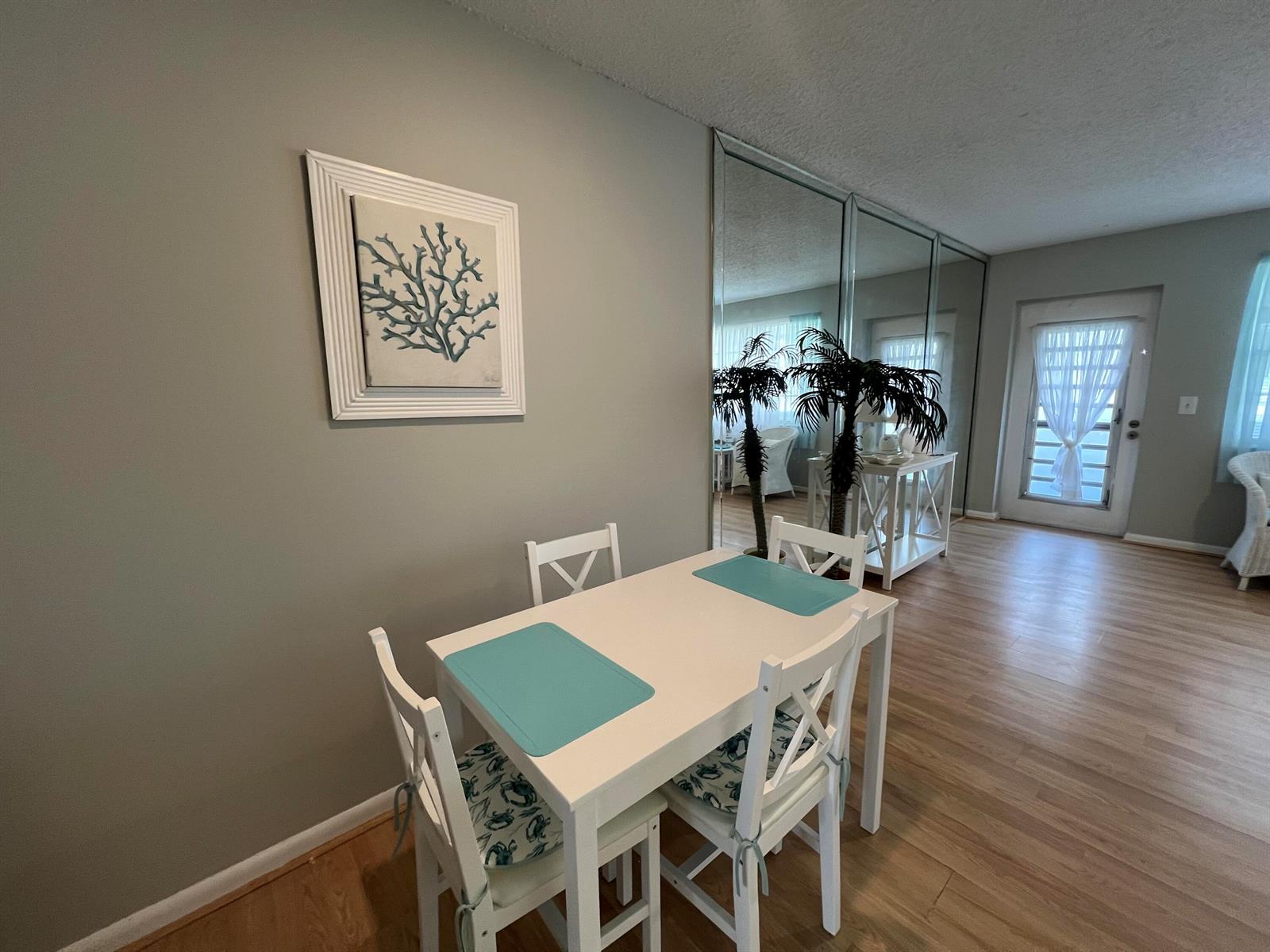 A dining area features a white table with four chairs, a coral wall art, and mirrors — 258 Markham L # 258, Deerfield Beach FL 33442, DEERFIELD BEACH, FL