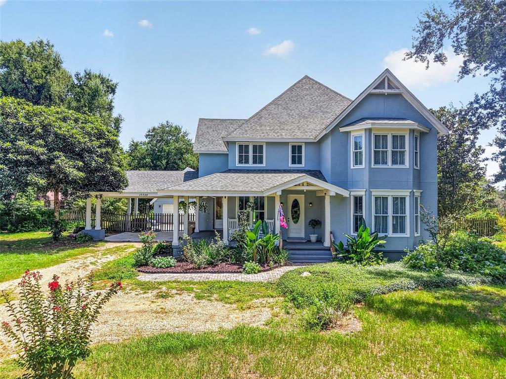 A blue two-story house with a wrap-around porch and a detached carport — 17730 COUNTY ROAD 448, MOUNT DORA, FL