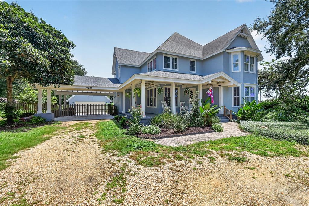 A two-story blue house with a wrap-around porch, gravel driveway, and detached garage — 17730 COUNTY ROAD 448, MOUNT DORA, FL