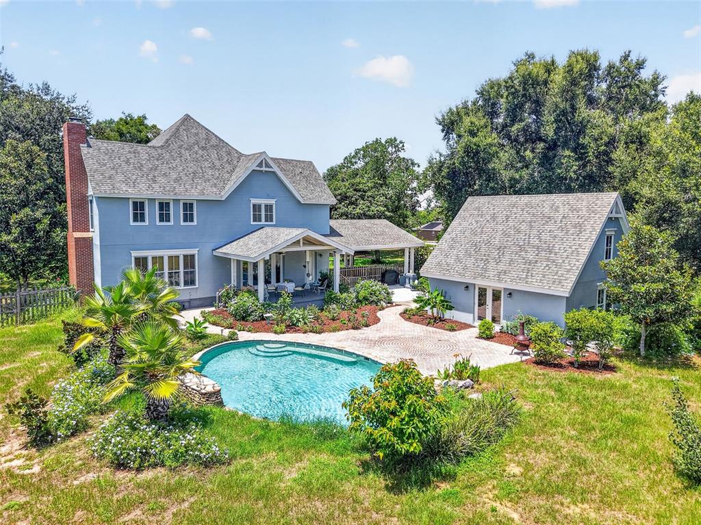 An aerial view shows a blue two-story house with a pool, patio, and detached garage — 17730 COUNTY ROAD 448, MOUNT DORA, FL