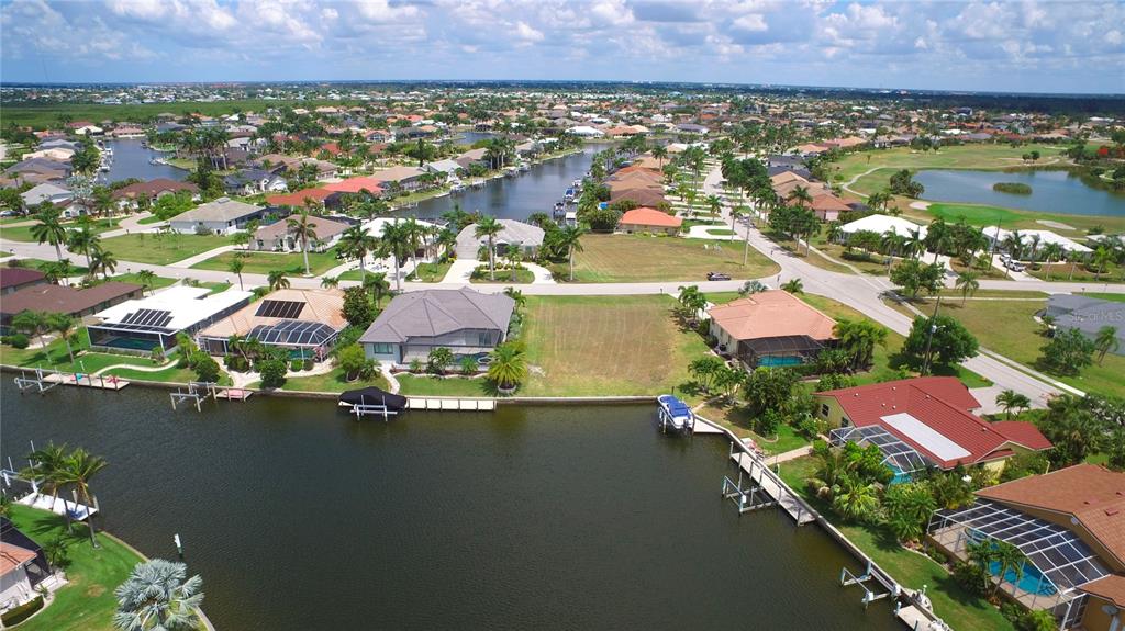 An aerial view shows a vacant waterfront lot situated between two houses along a canal — 507 MADRID BOULEVARD, PUNTA GORDA, FL