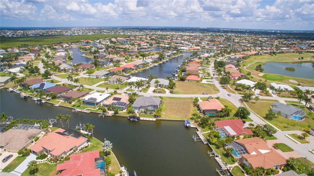 An aerial view of a residential neighborhood featuring houses with pools along a canal — 507 MADRID BOULEVARD, PUNTA GORDA, FL