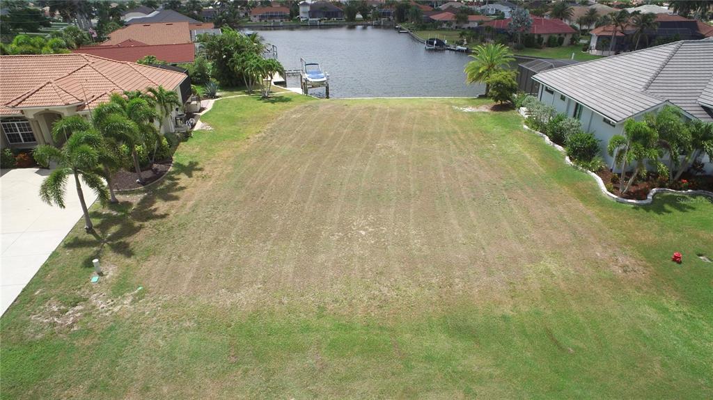 An aerial view of a vacant waterfront lot situated between two residential houses — 507 MADRID BOULEVARD, PUNTA GORDA, FL