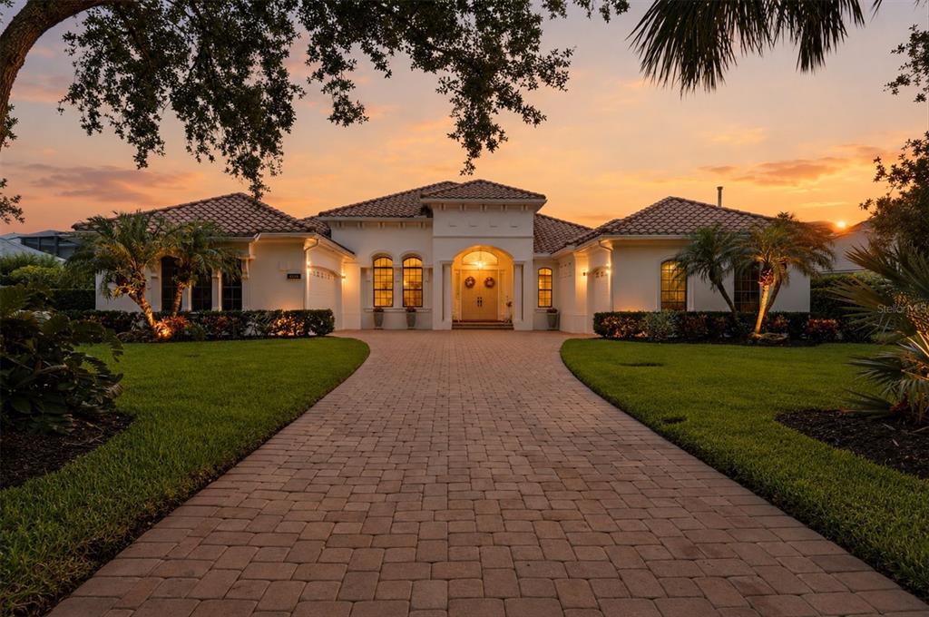 A single-story stucco house with a tile roof and a paved driveway at sunset — 3548 FOUNDERS CLUB DRIVE, SARASOTA, FL