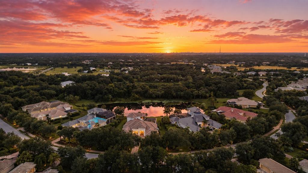 An aerial view of a suburban neighborhood surrounding a pond at sunset — 3548 FOUNDERS CLUB DRIVE, SARASOTA, FL
