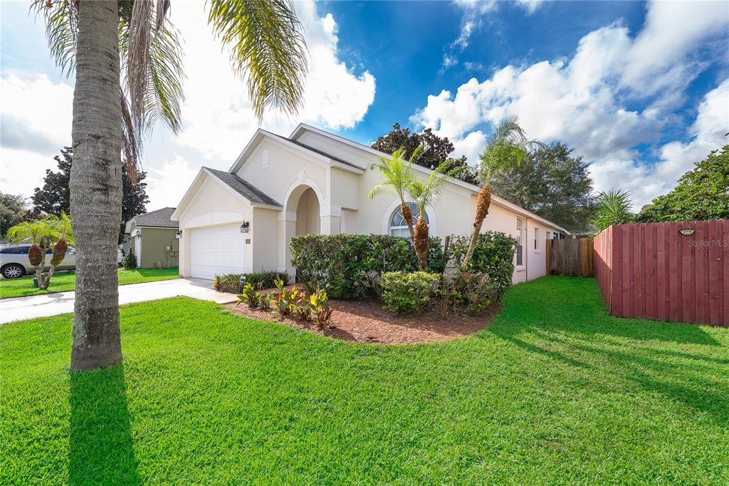 A single-story house with a white garage, arched entryway, and a red wooden fence — 13233 HEMING WAY, ORLANDO, FL