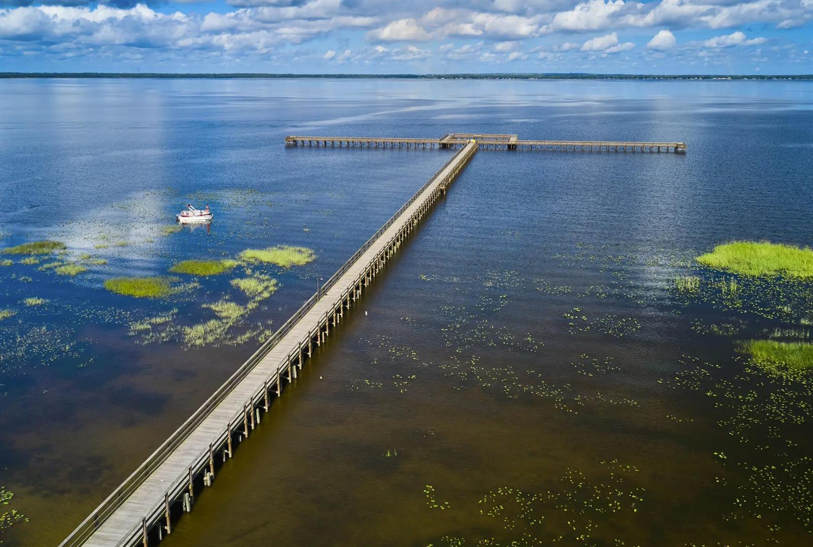 An aerial view shows a long wooden pier extending into a large, calm lake — 1022 Portulaca Drive, FL 33855, FL