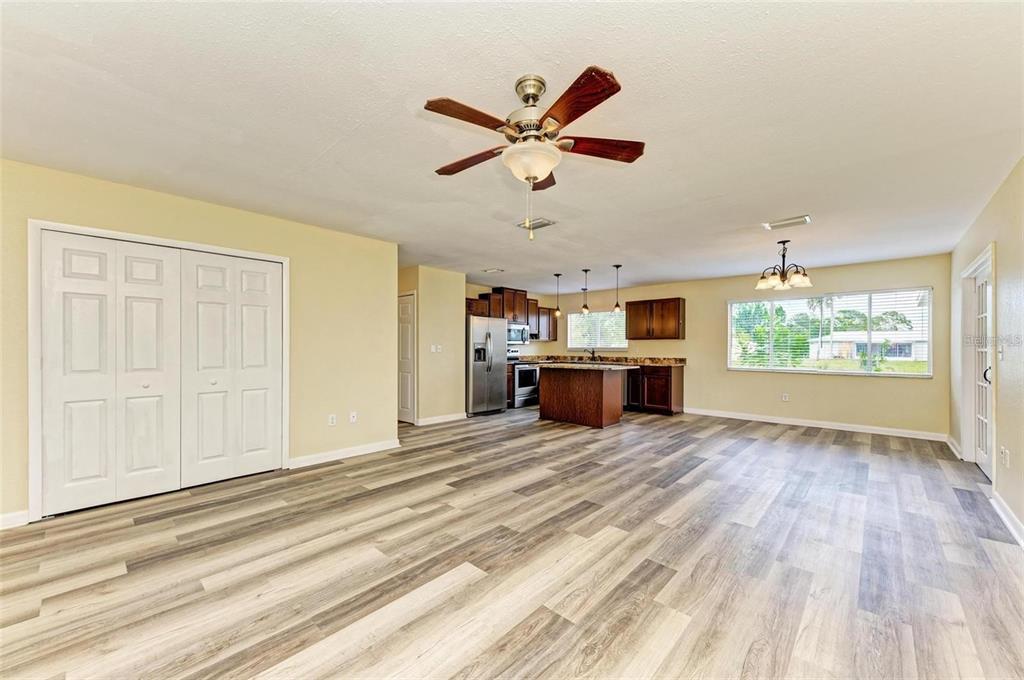 An open-concept living area with wood-look flooring, a ceiling fan, and an adjacent kitchen — 7120 ELYTON DRIVE, NORTH PORT, FL