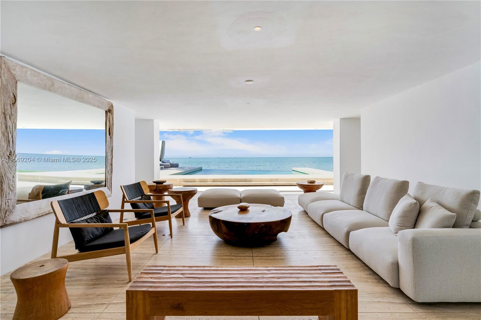 A modern living room features a large sectional sofa, wooden furniture, and an ocean view — 440 S Mashta Dr, Key Biscayne FL 33149, KEY BISCAYNE, FL