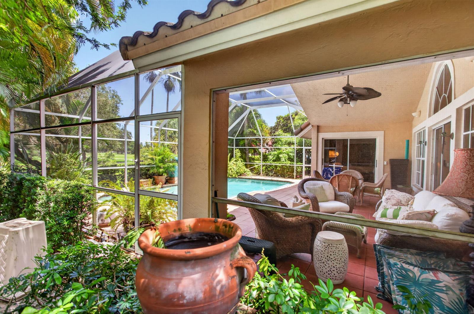 A screened-in patio features wicker furniture, a swimming pool, and views of a golf course — 526 Misty Oaks Drive, Pompano Beach FL 33069, POMPANO BEACH, FL