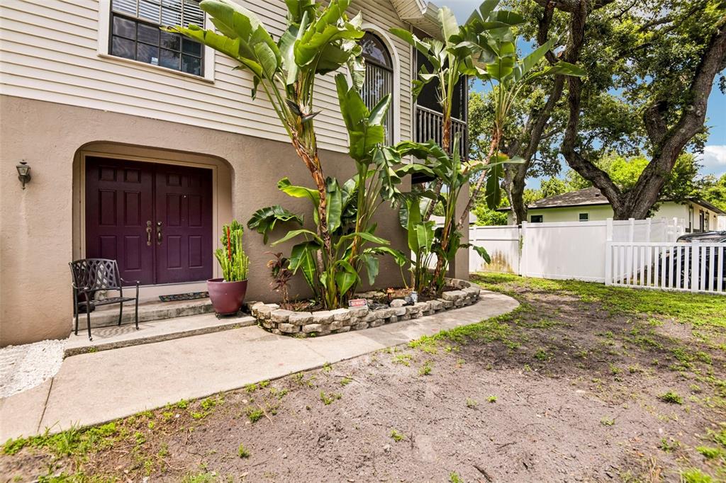 A house exterior features a dark purple double door, a concrete walkway, and large tropical plants — 5831 114TH TERRACE N, PINELLAS PARK, FL
