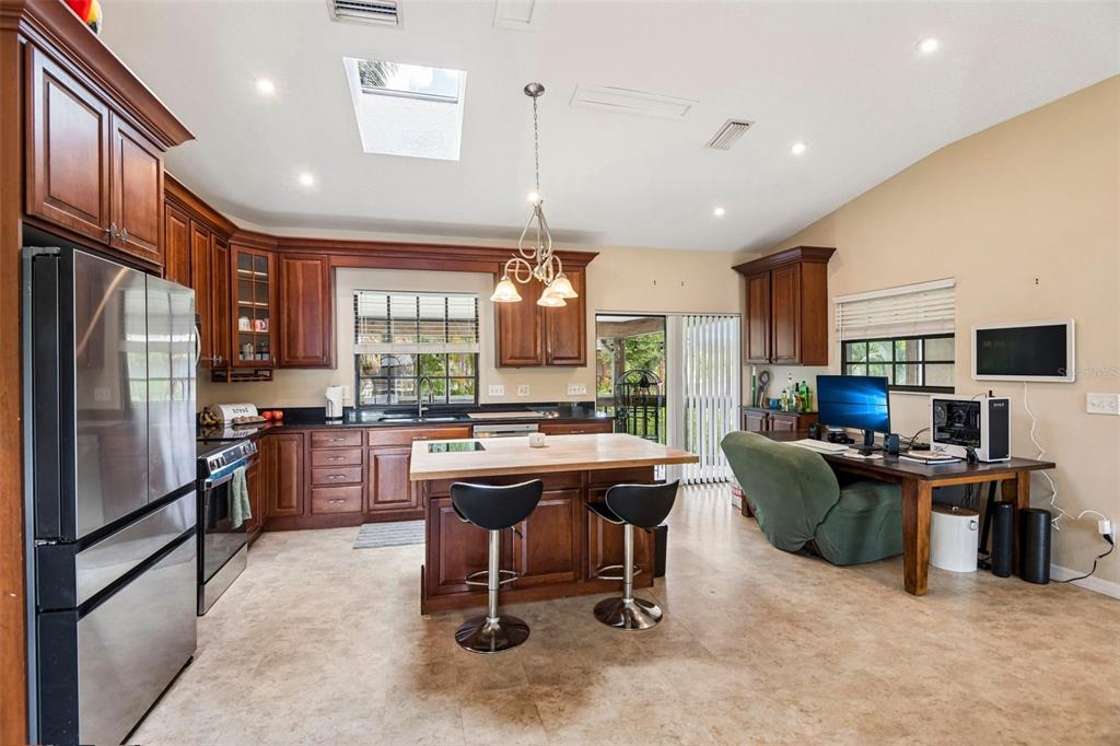 A kitchen with wood cabinets, a central island, stainless steel appliances, and an attached desk — 5831 114TH TERRACE N, PINELLAS PARK, FL