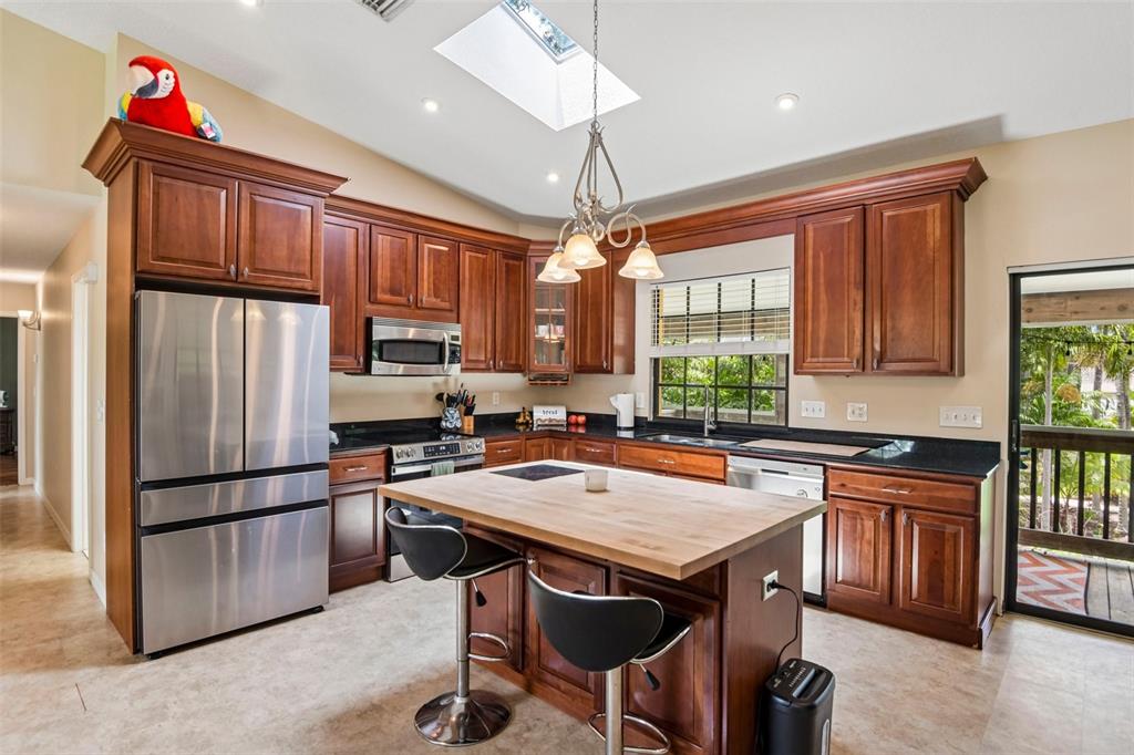 A kitchen with wood cabinets, stainless steel appliances, a butcher block island, and a skylight — 5831 114TH TERRACE N, PINELLAS PARK, FL