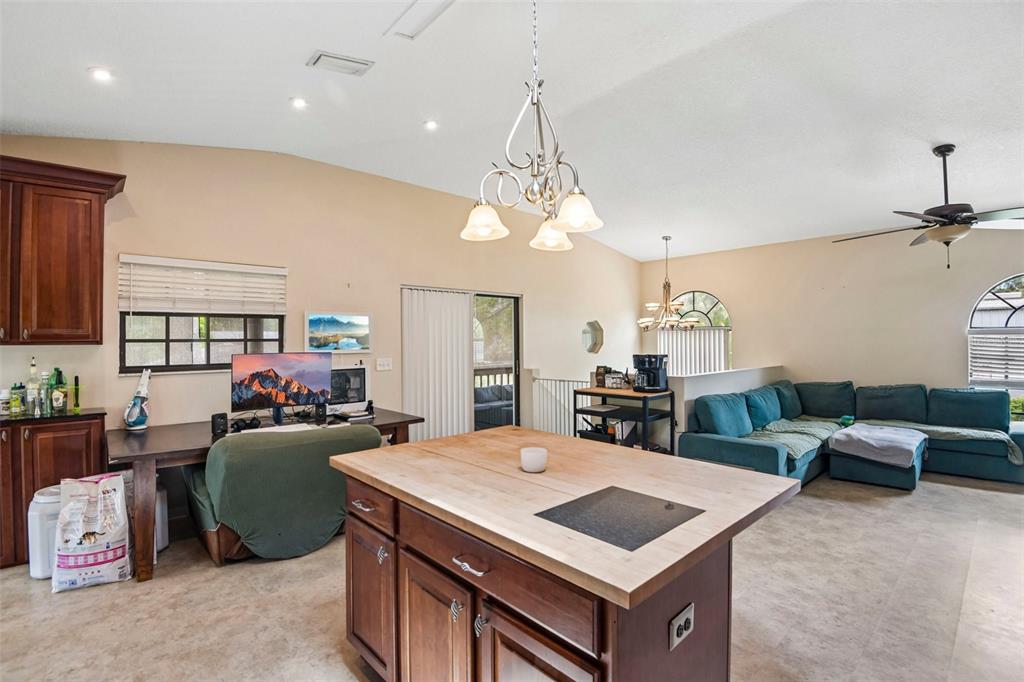 A kitchen island with a wood countertop sits in an open-concept room with a living area — 5831 114TH TERRACE N, PINELLAS PARK, FL