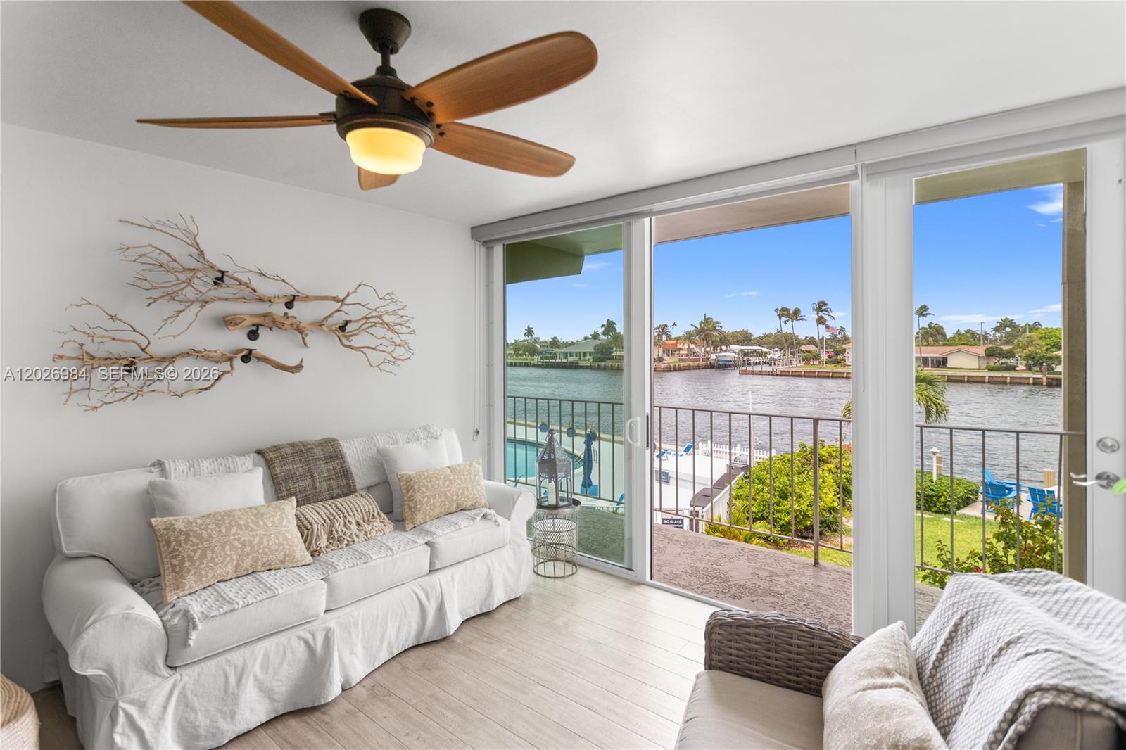 A living room with a white sofa, ceiling fan, and sliding doors overlooking a canal — 743 N Riverside Dr # 4B, Pompano Beach FL 33062, POMPANO BEACH, FL