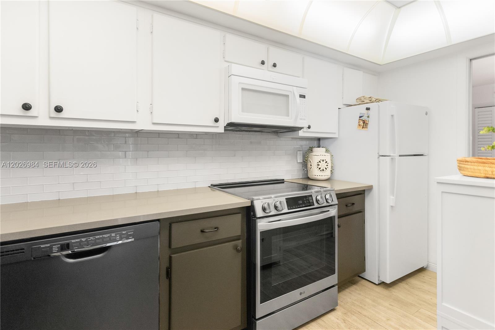 A kitchen features white upper cabinets, dark lower cabinets, stainless steel appliances, and subway tile — 743 N Riverside Dr # 4B, Pompano Beach FL 33062, POMPANO BEACH, FL