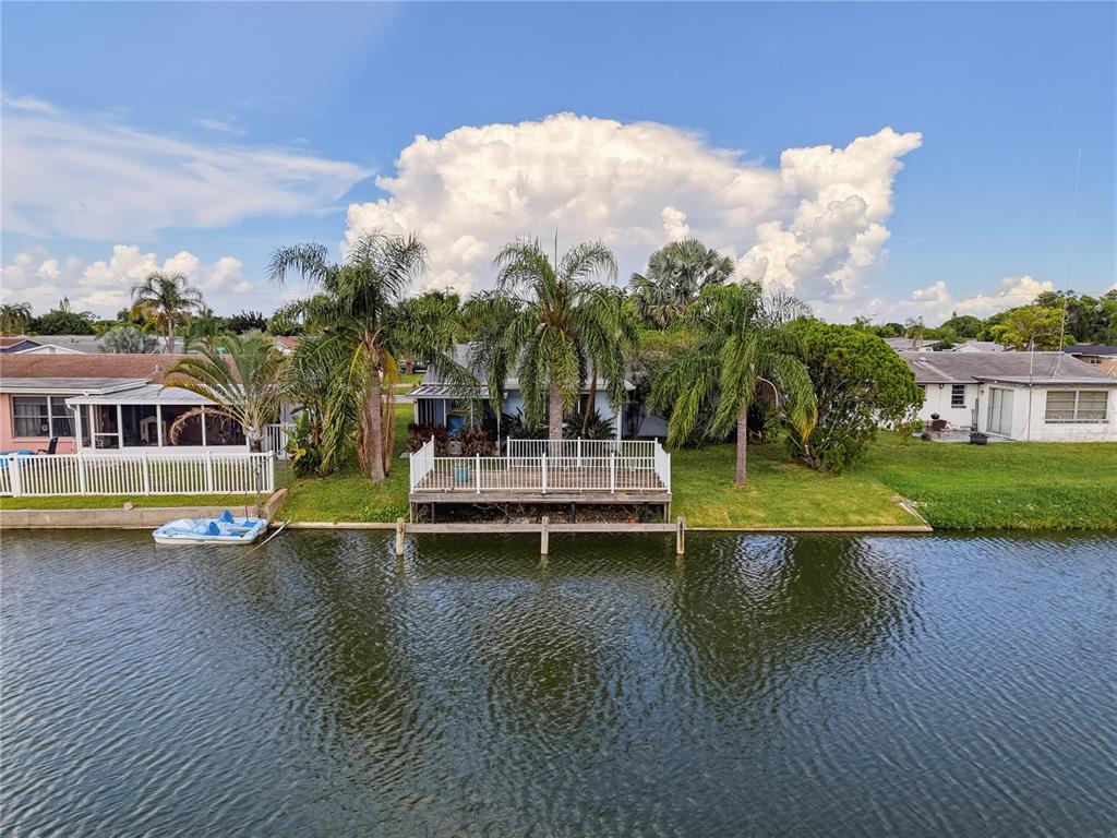 An aerial view shows a waterfront house with a wooden deck and palm trees — 2228 SOCIETY DRIVE, HOLIDAY, FL