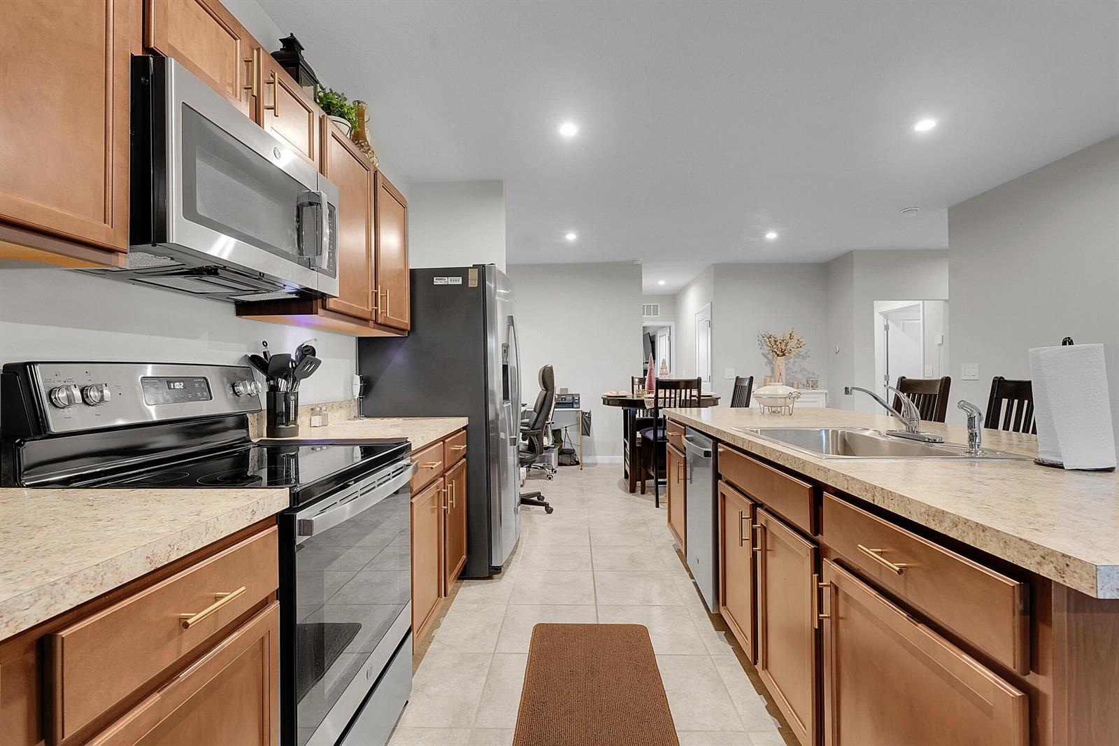 A kitchen with wood cabinets, stainless steel appliances, and a central island with a sink — 333 Raspberry Road, Fort Pierce FL 34981, FORT PIERCE, FL