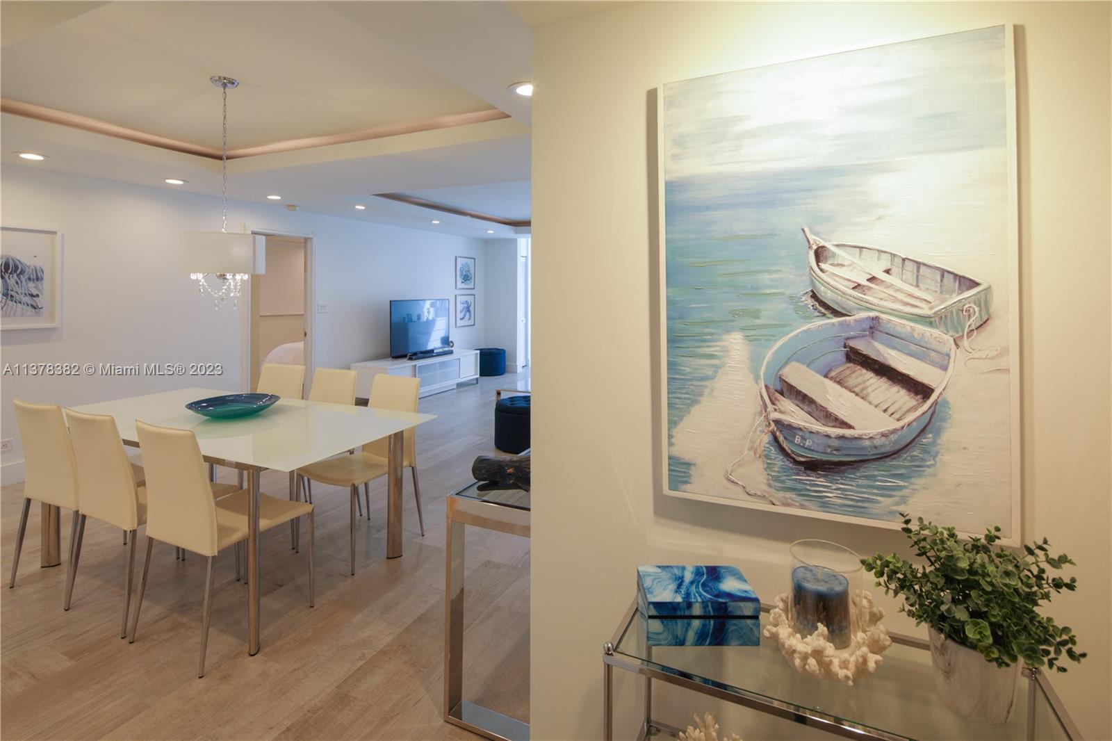 A dining area with a white table and chairs sits adjacent to a living room — 5005 Collins Ave # 610, Miami Beach FL 33140, MIAMI BEACH, FL