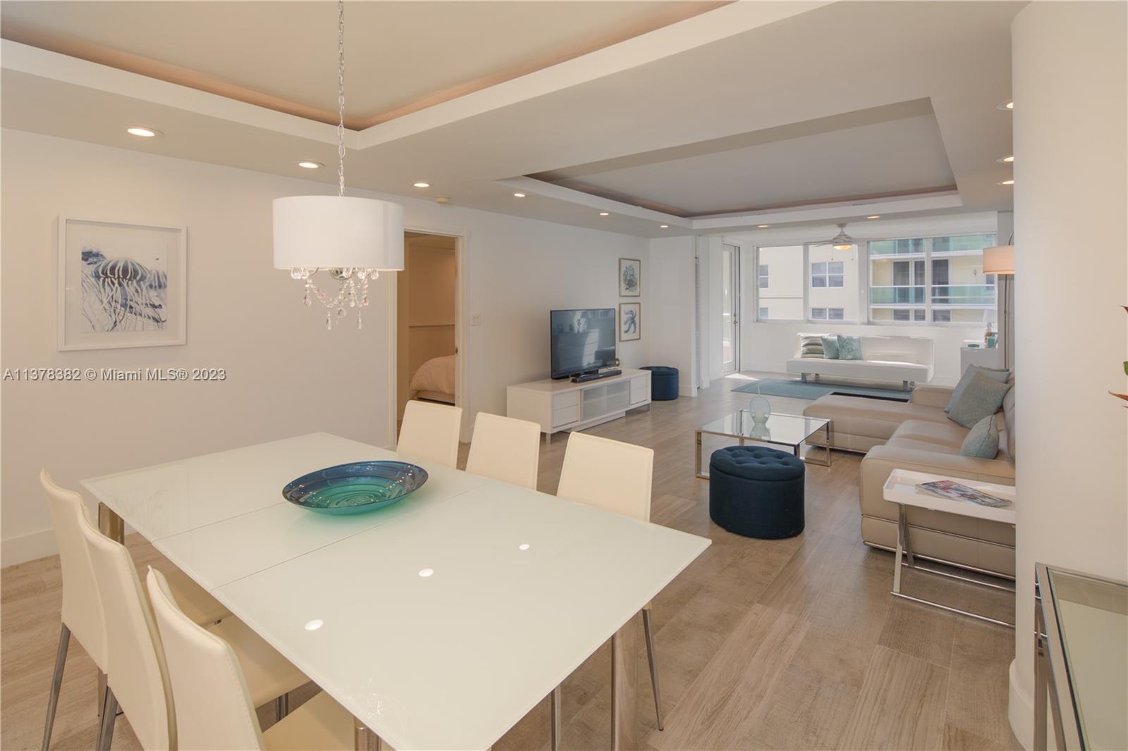 A bright, open-concept living and dining area features white furniture, light wood floors, and recessed lighting — 5005 Collins Ave # 610, Miami Beach FL 33140, MIAMI BEACH, FL