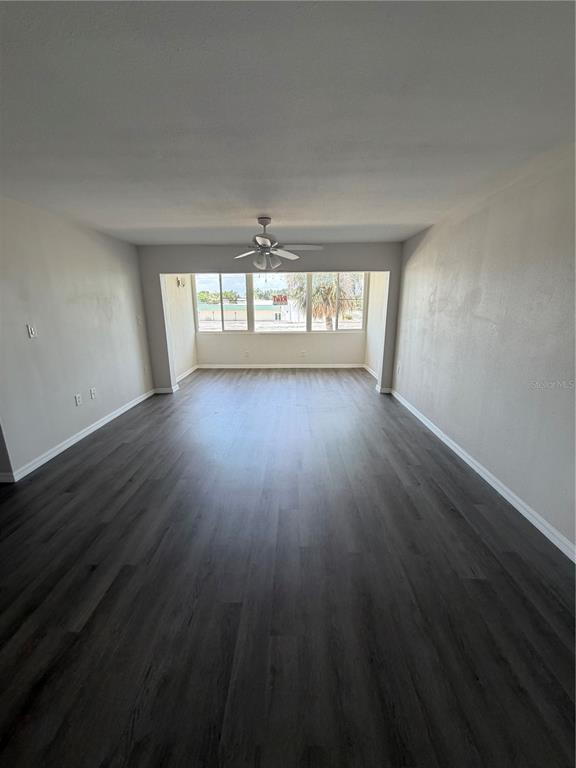 An empty room features dark wood-look flooring, white walls, and a ceiling fan — 21287 GERTRUDE AVENUE UNIT 208, PORT CHARLOTTE, FL