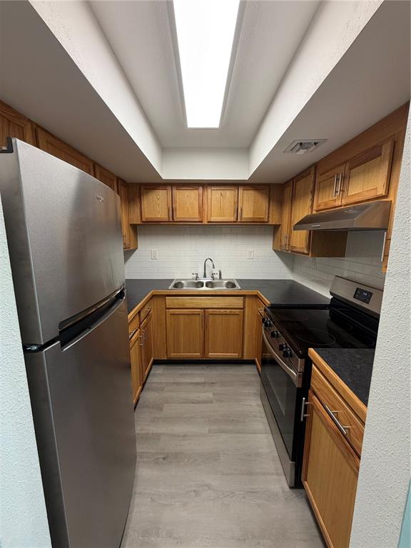 A galley kitchen features oak cabinets, stainless steel appliances, and a white subway tile backsplash — 21287 GERTRUDE AVENUE UNIT 208, PORT CHARLOTTE, FL