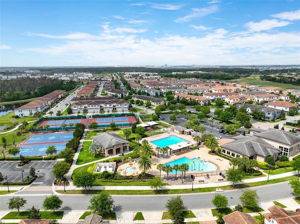 An aerial view shows a residential community with a swimming pool, tennis courts, and houses — 9956 EAGLE CREEK CENTER BLVD, ORLANDO, FL