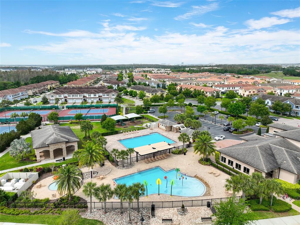 An aerial view shows a community swimming pool, splash pad, and tennis courts near houses — 9956 EAGLE CREEK CENTER BLVD, ORLANDO, FL