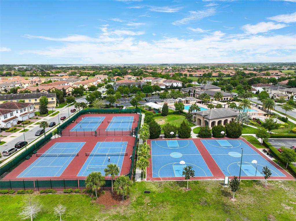 An aerial view shows two tennis courts and two basketball courts in a residential community — 9956 EAGLE CREEK CENTER BLVD, ORLANDO, FL