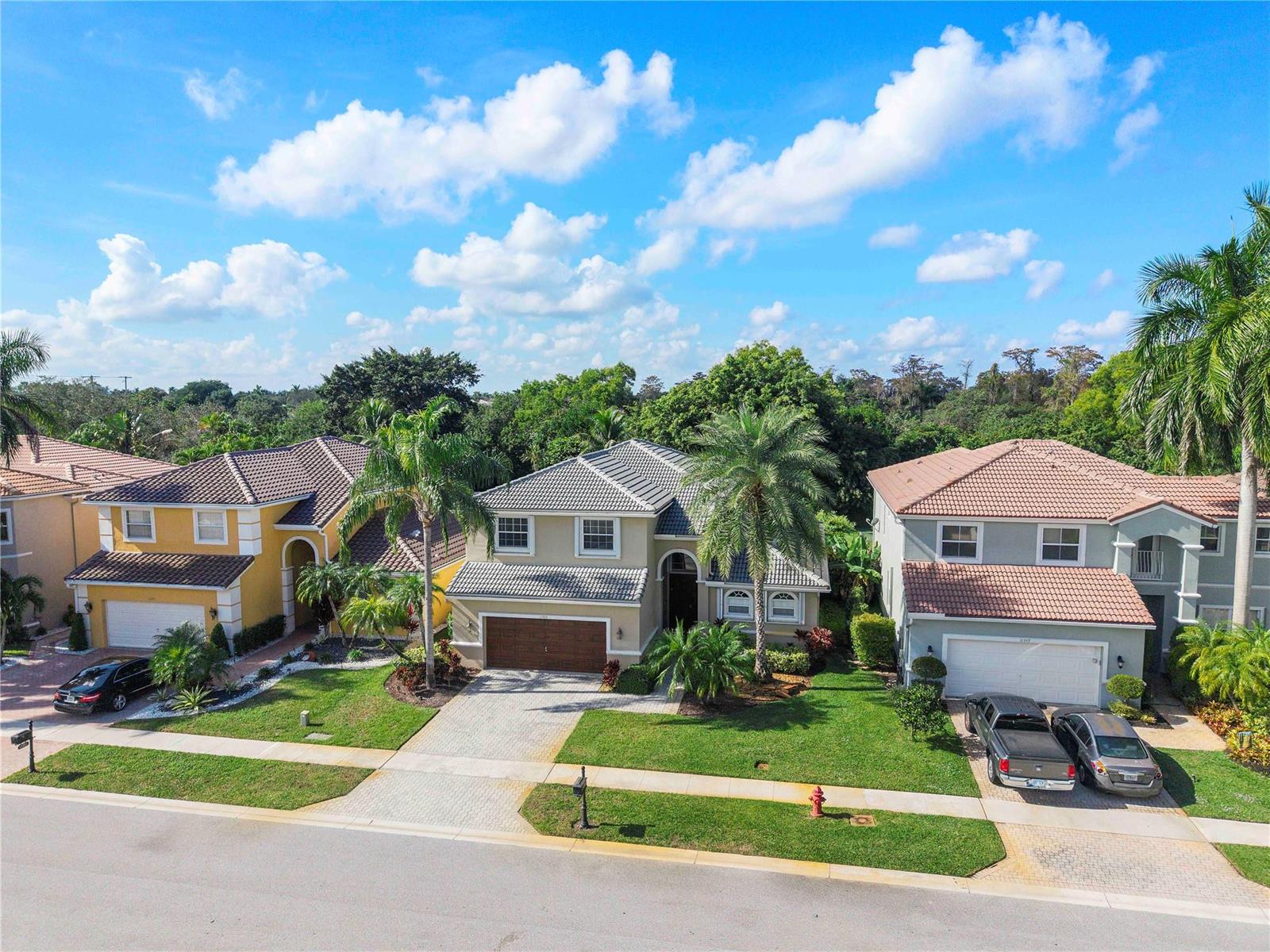 An aerial view of three suburban houses with tile roofs and driveways on a sunny day — 11353 Sea Grass Circle, Boca Raton FL 33498, BOCA RATON, FL