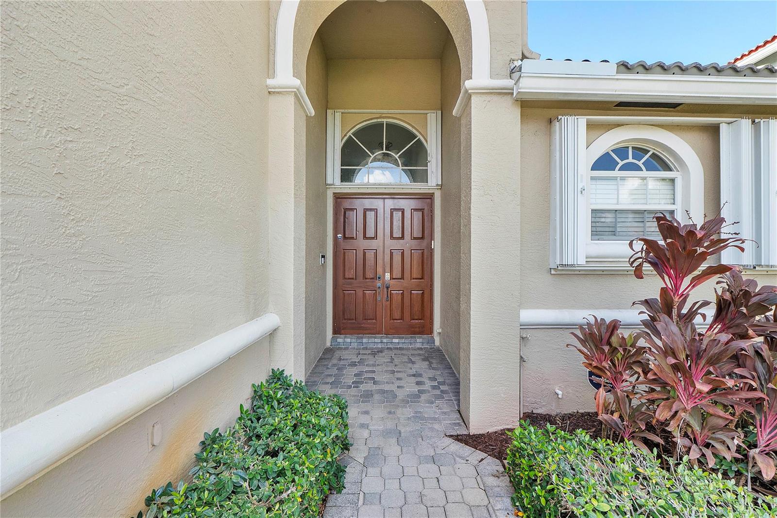 The exterior entryway features a double wooden door, a stone walkway, and arched windows — 11353 Sea Grass Circle, Boca Raton FL 33498, BOCA RATON, FL