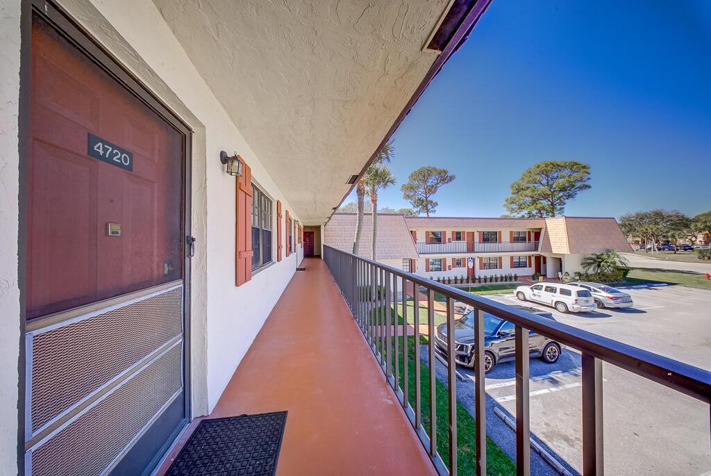 An exterior walkway with a metal railing overlooks a parking lot at an apartment complex — 4720 Oak Terrace Drive, FL 33463, FL