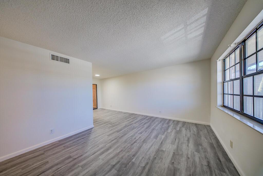 An empty room with gray wood-look flooring, white walls, and a large grid-pane window — 4720 Oak Terrace Drive, FL 33463, FL