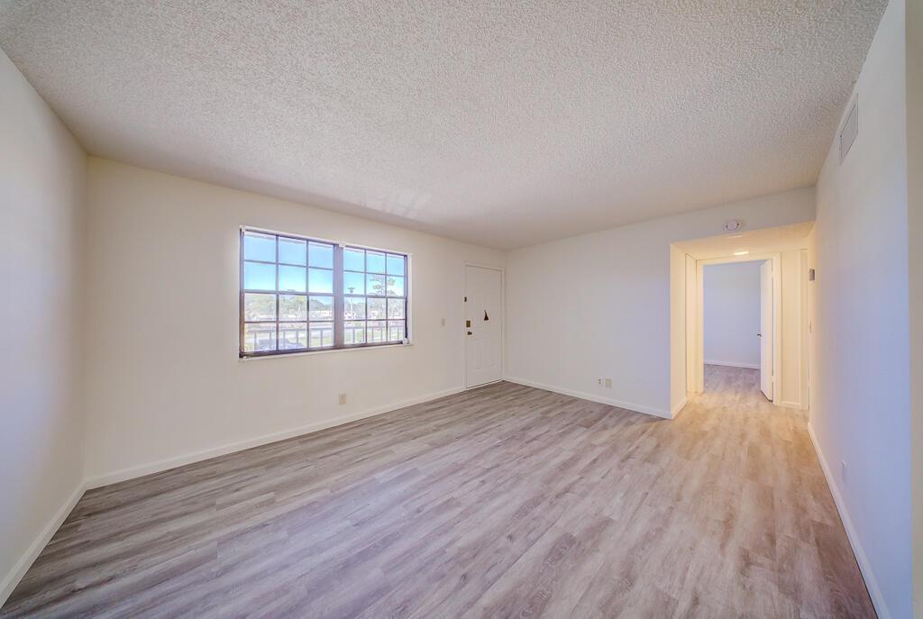 An empty room features light wood-look flooring, white walls, a window, and a doorway — 4720 Oak Terrace Drive, FL 33463, FL