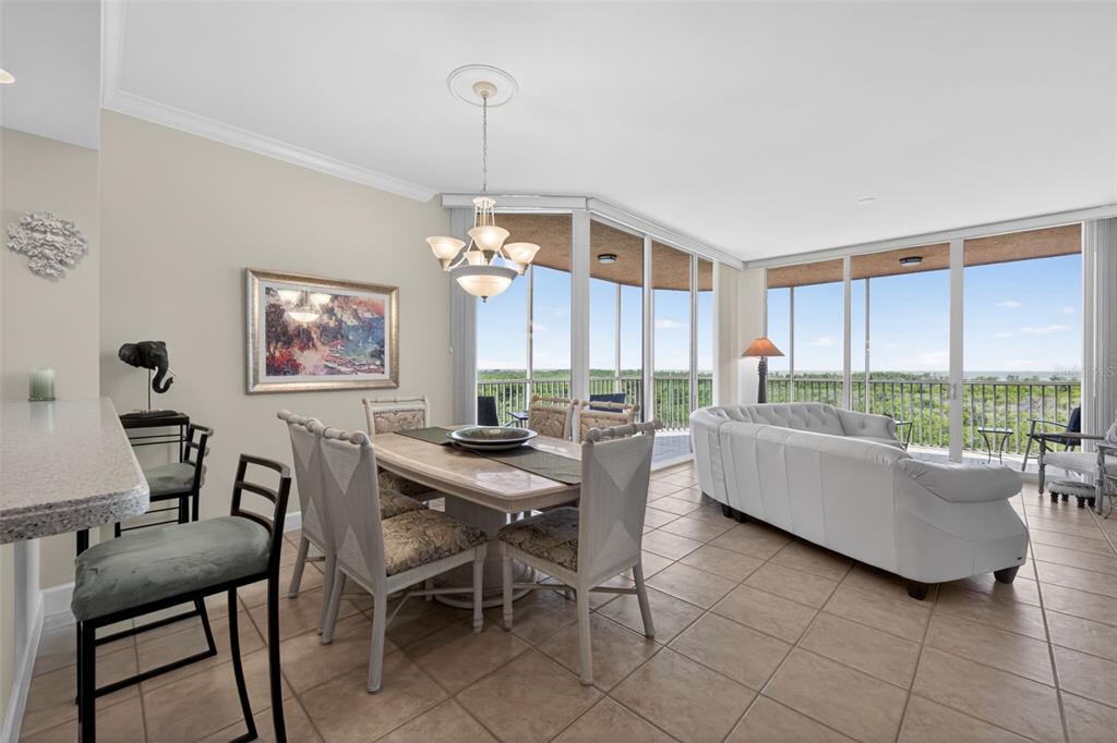 A dining area and living room feature tile floors, a chandelier, and floor-to-ceiling windows — 3191 MATECUMBE KEY ROAD UNIT 202, PUNTA GORDA, FL