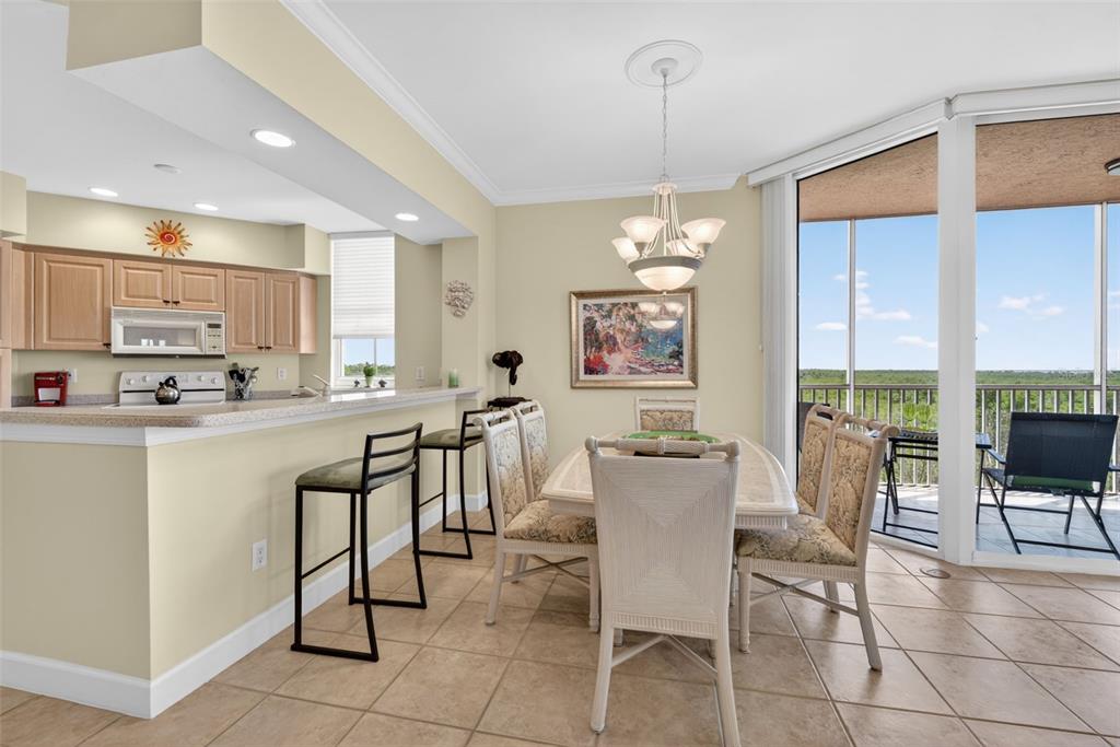 A dining area with a breakfast bar, tile floors, and a balcony with outdoor seating — 3191 MATECUMBE KEY ROAD UNIT 202, PUNTA GORDA, FL