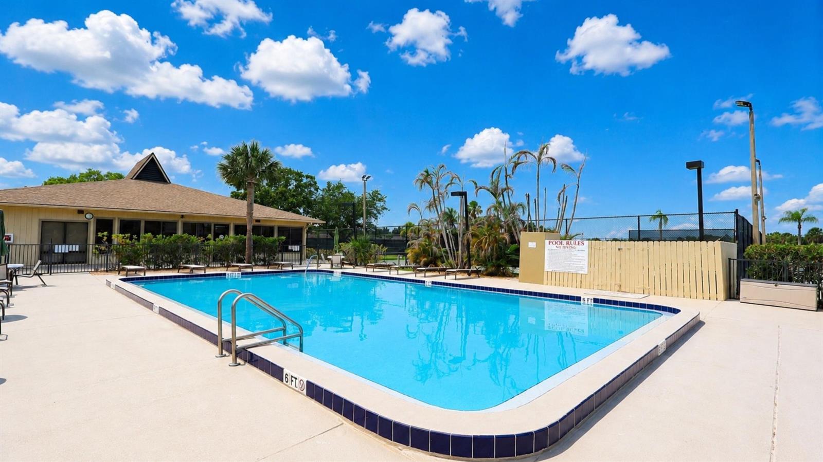 A rectangular outdoor swimming pool with a blue tiled edge sits on a concrete deck — 29 Plantation Drive # 202, Vero Beach FL 32966, VERO BEACH, FL