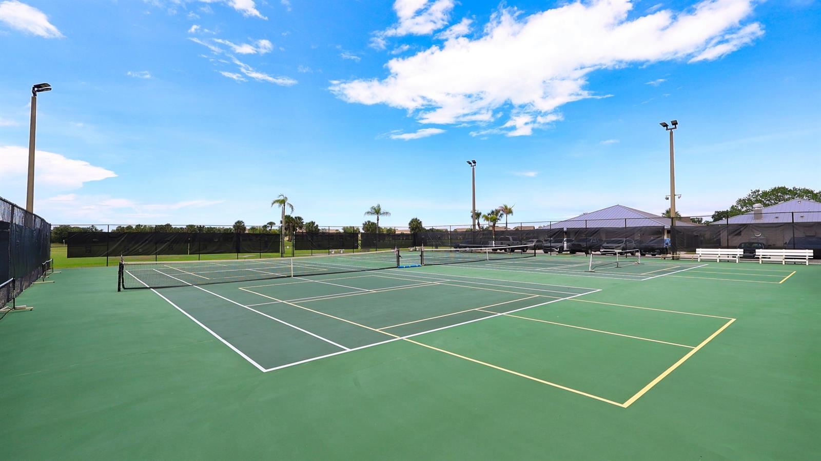An outdoor tennis court with green surfacing, white boundary lines, and surrounding black fencing — 29 Plantation Drive # 202, Vero Beach FL 32966, VERO BEACH, FL