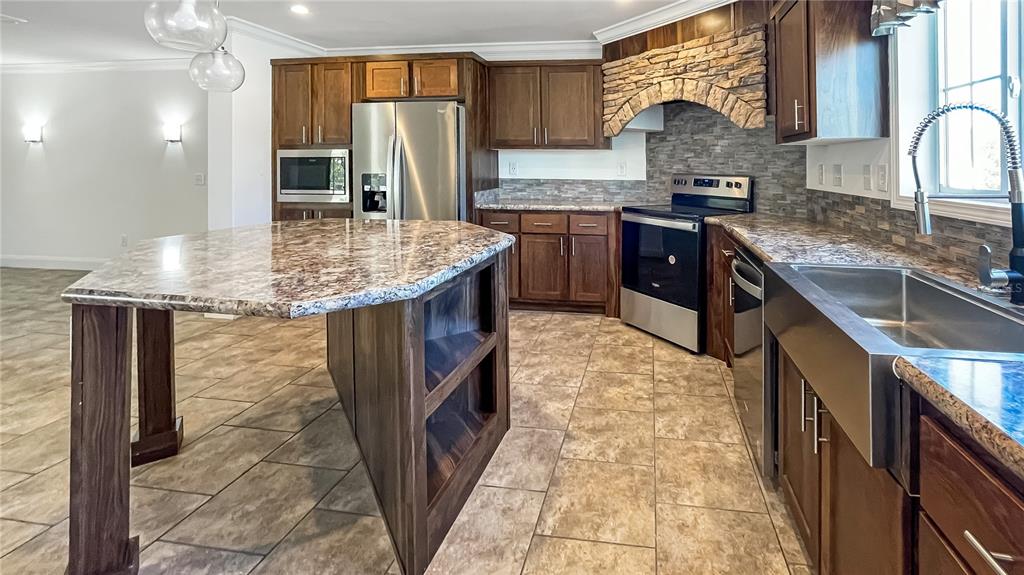 A kitchen features dark wood cabinets, granite countertops, a stone range hood, and a center island — 9896 SCEPTER AVENUE, BROOKSVILLE, FL