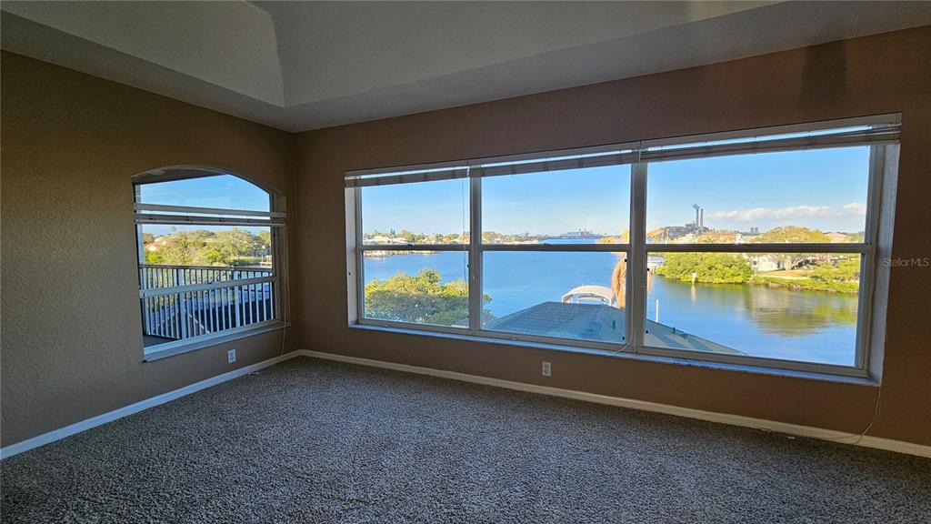 An empty room with beige walls, carpeted flooring, and large windows overlooking a waterway — 1209 APOLLO BEACH BOULEVARD, APOLLO BEACH, FL